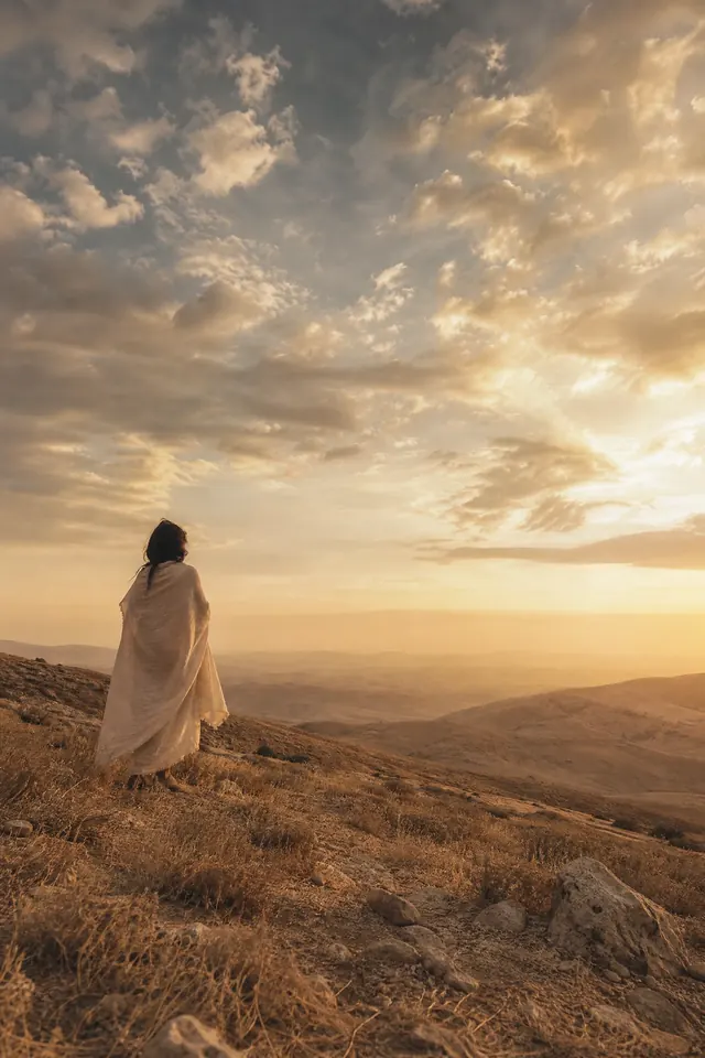 A solitary figure standing quietly at a warm sunrise horizon — hope, peace, and coming home to yourself