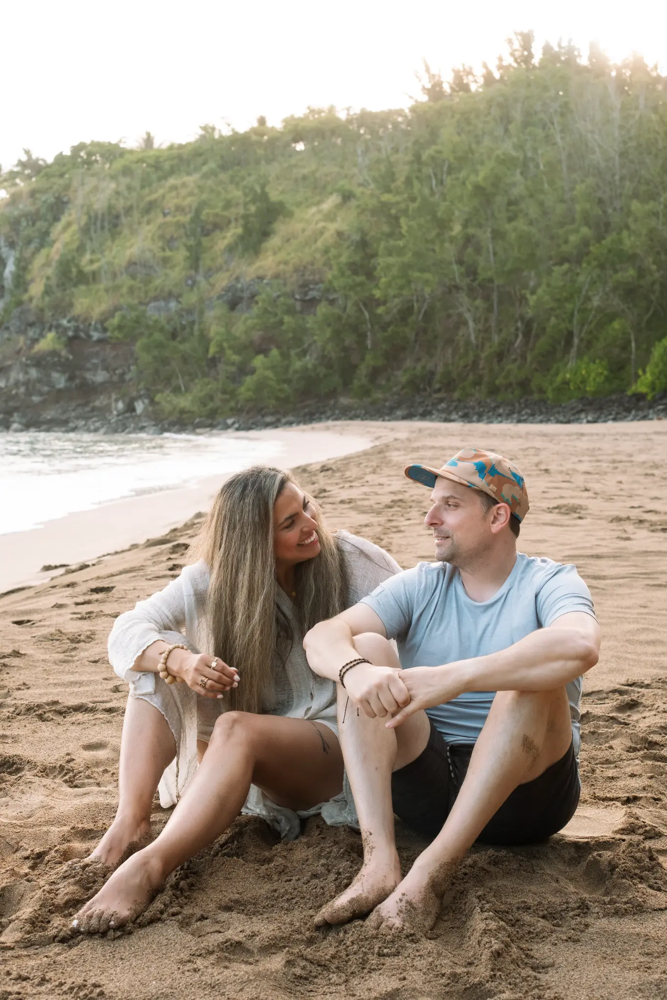 Angela Soto and John Bolos sitting together on the beach