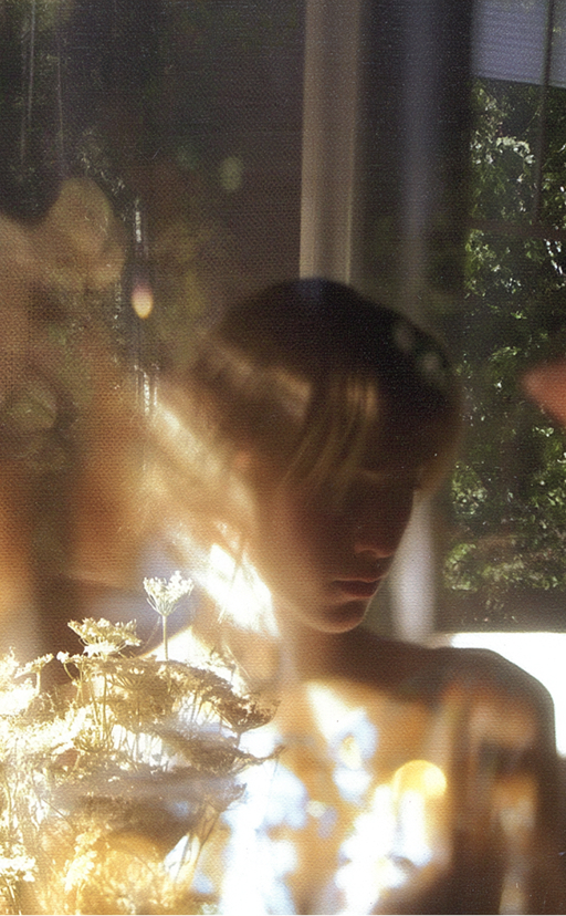 A contemplative figure layered with natural light and foliage